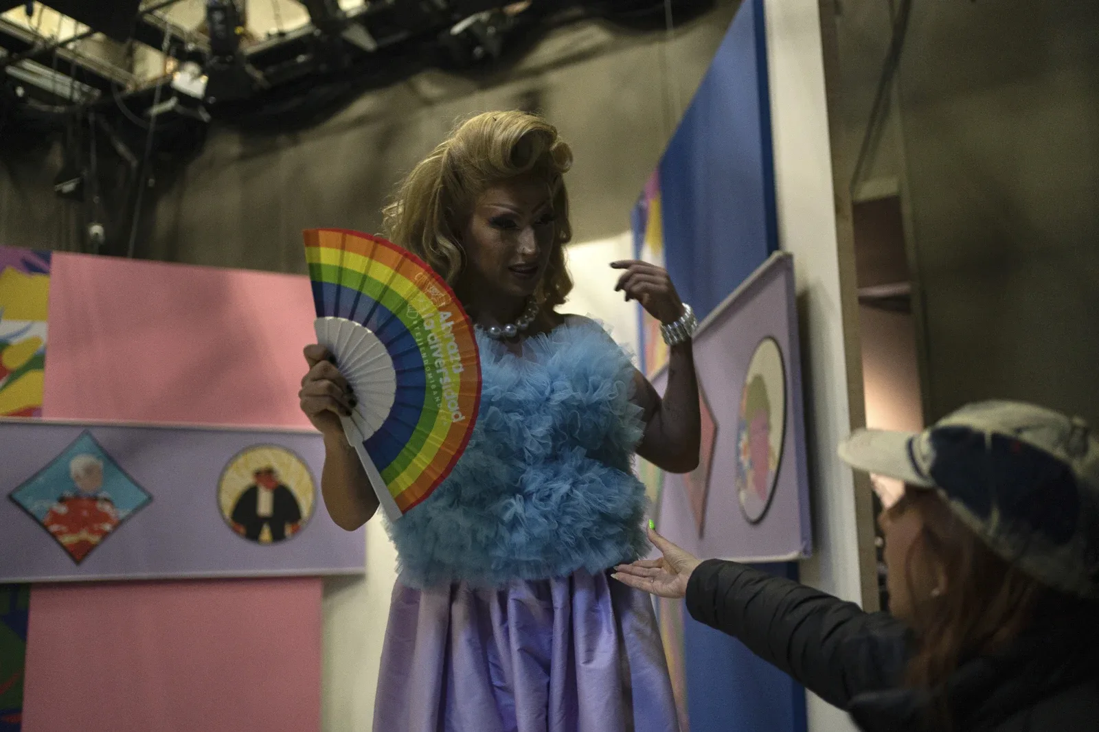 Amanda, the first-ever drag queen to host a news program for Mexican TV, steps off her set while holding a rainbow fan in memory of magistrate Ociel Baena, at the end of her Canal Once newscast “La Verdrag”, in Mexico City, Wednesday, Nov. 15, 2023. Donning a blazer, silver pumps shrouded by a white skirt and their signature rainbow fan, it would be the last TV interview the magistrate would ever give. (AP Photo/Aurea Del Rosario)